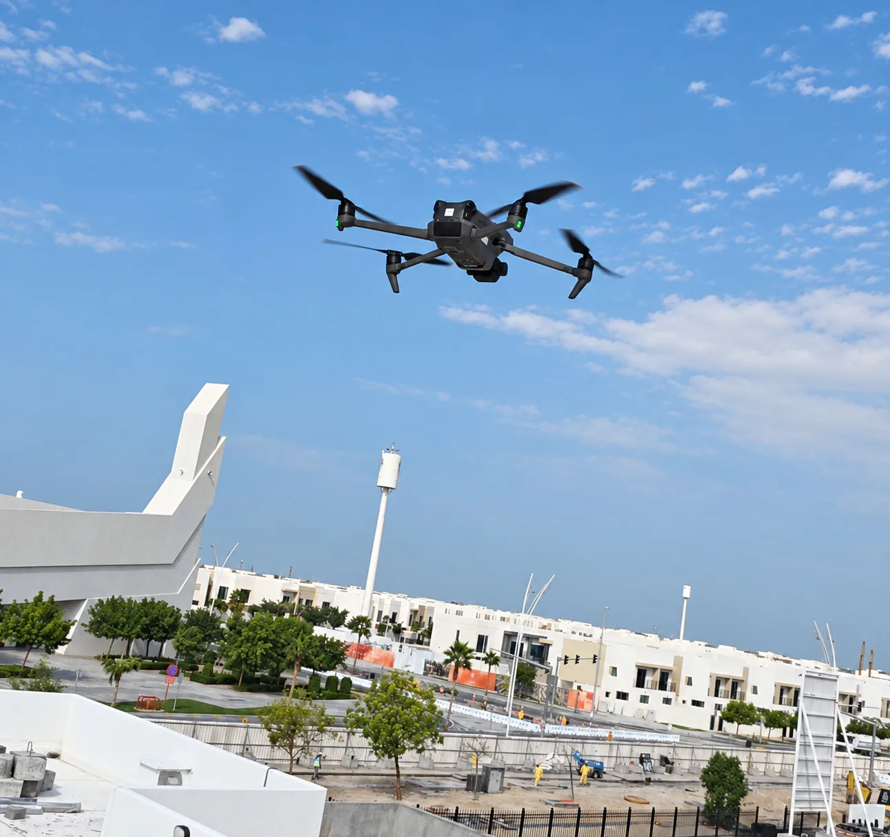 A drone hovers above landscaped areas and white residential buildings at The Sustainable City on Yas Island, Abu Dhabi