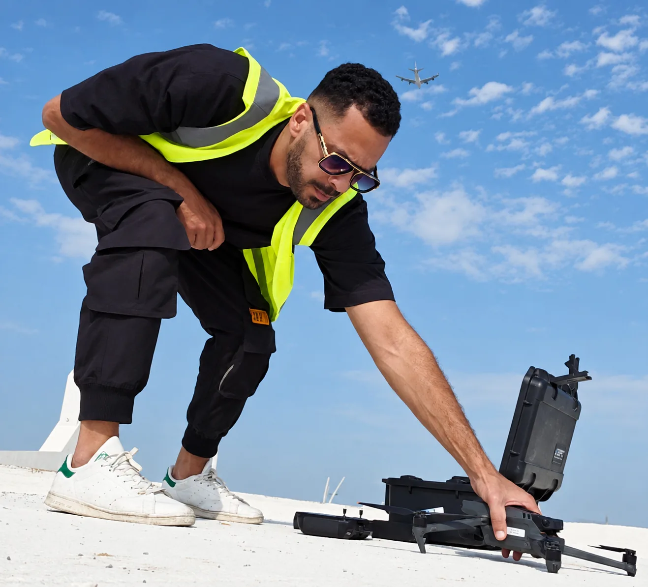 A pilot wearing a high-visibility vest handles a drone beside an open equipment case on a rooftop at The Sustainable City, Yas Island, Abu Dhabi