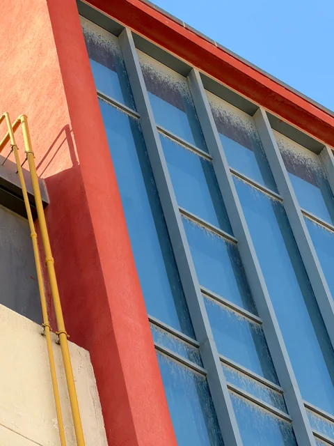 Red building façade and tall windows before cleaning
