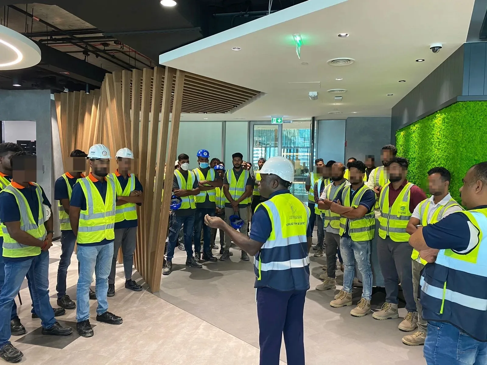 A group wearing safety vests gathers for a briefing inside a building